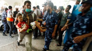 Palestinian carries a boy, who medics said was wounded during heavy Israeli shelling at the Shejaia district, at a hospital in Gaza City